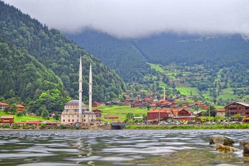 A mosque with two minarets, a river, and a mountainous landscape with a village. 3