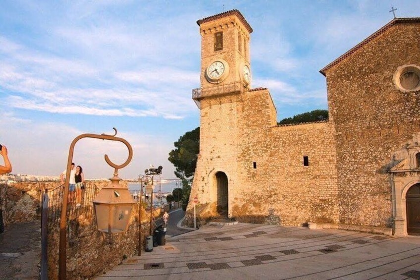 A historic stone building with a clock tower, a gate, and a clear sky. 2