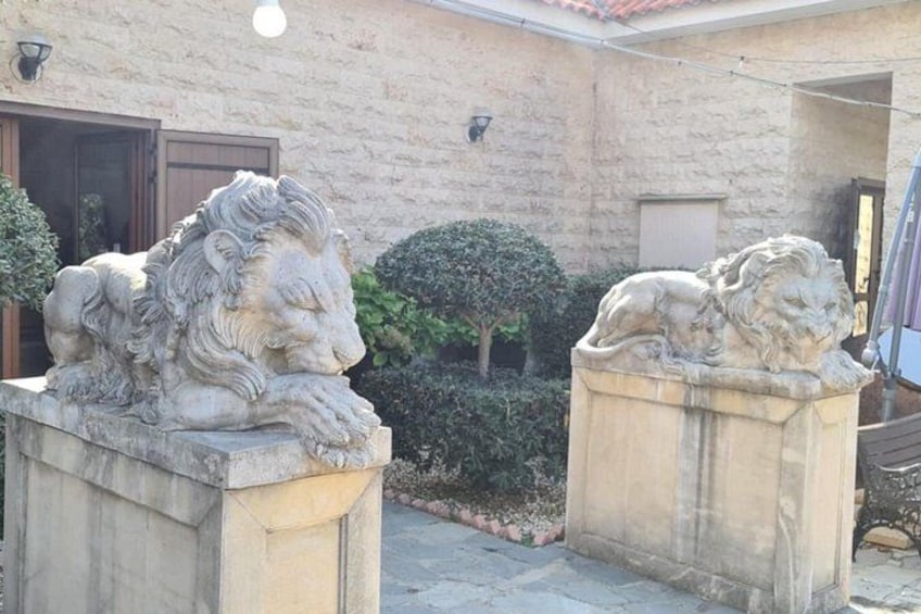 Two stone lion statues in a courtyard with a building in the background. 2