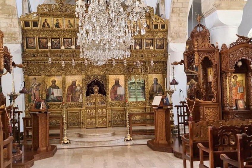 An ornate religious interior with golden decorations, a chandelier, and religious icons. 4