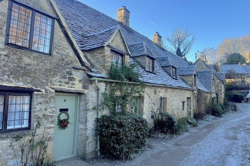 A row of stone houses with a green door, a wreath, and a gravel path. 3