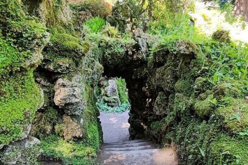 A moss-covered rock formation with a narrow passageway leading through it. 5