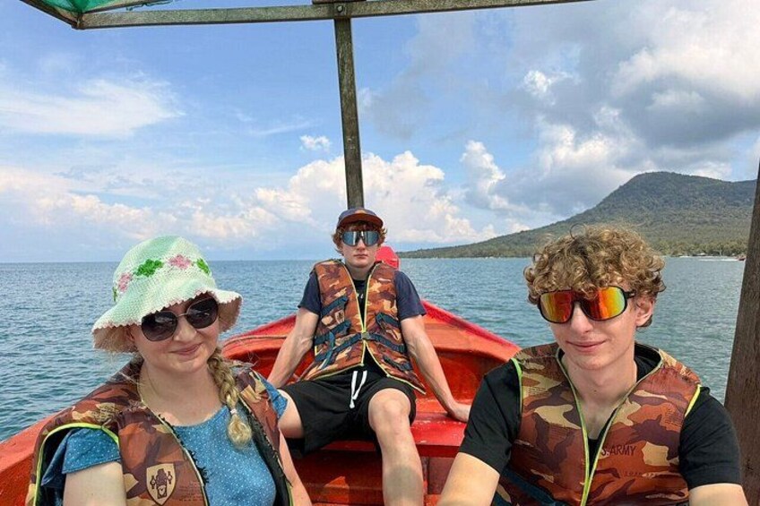 Tres personas en un bote frente a un paisaje montañoso. 4