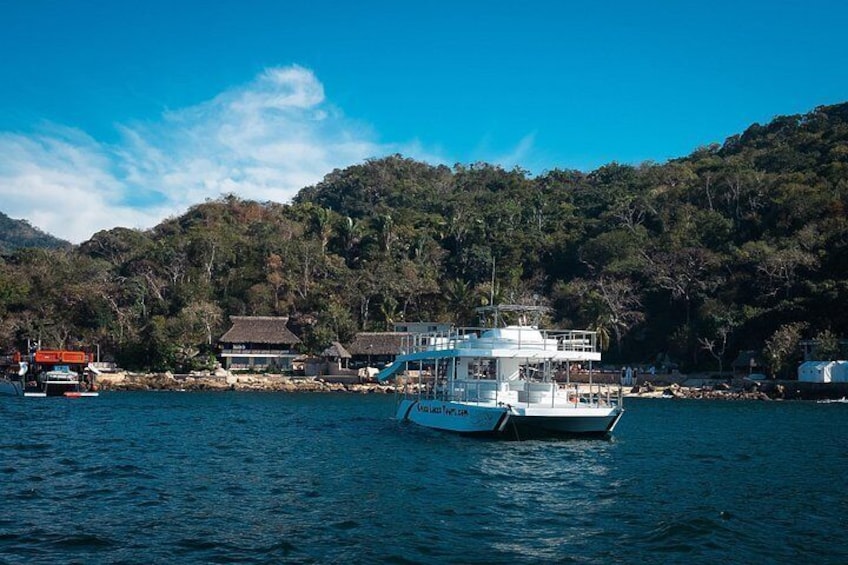 A boat on a calm body of water with a forested hillside in the background. 2