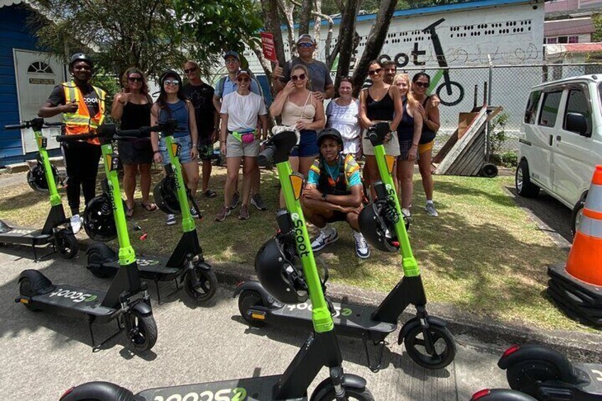 A group of people posing with electric scooters in an outdoor setting. 5