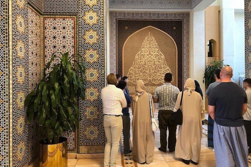 A group of people in a room with intricate tile patterns and a large decorative archway. 4