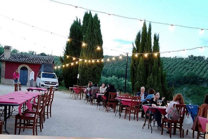 An outdoor dining area with tables and chairs, string lights, and a van in the background. 4