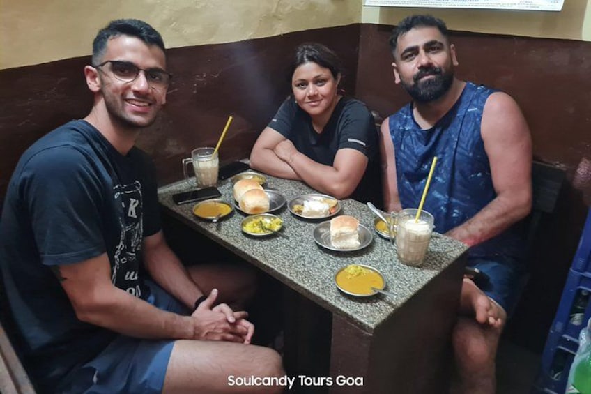 Three people sitting at a table with food and drinks. 2