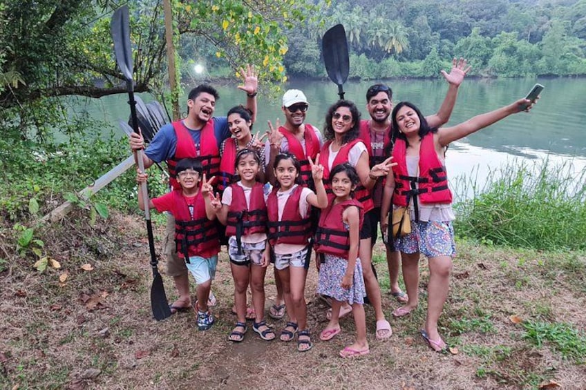 A group of people in red life jackets by a lake, some holding paddles. 1