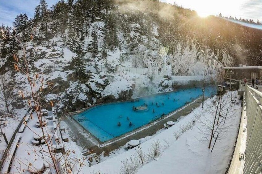 A swimming pool surrounded by snow-covered trees and a mountainous landscape. 2