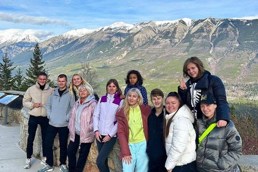 A group of people standing on a mountain trail with snow-capped mountains in the background. 4
