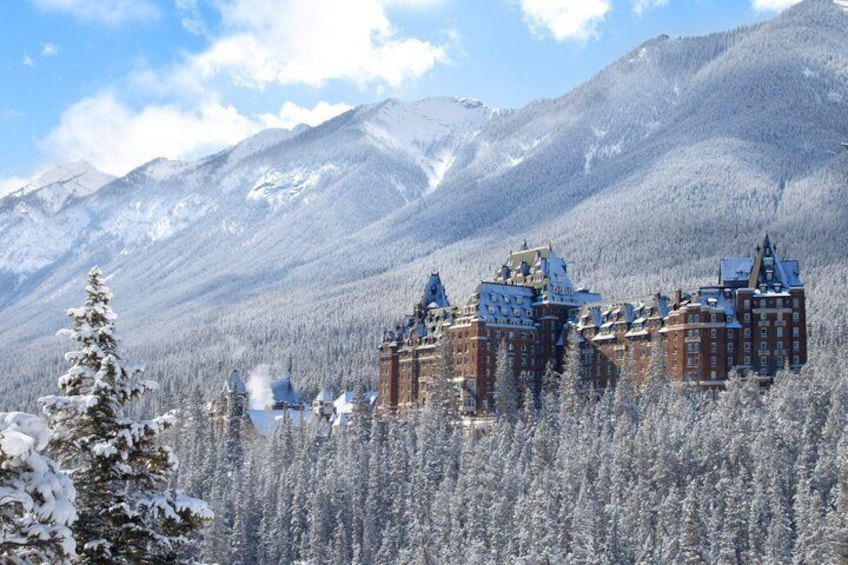 A snow-covered mountain range with a historic building complex in the foreground. 5