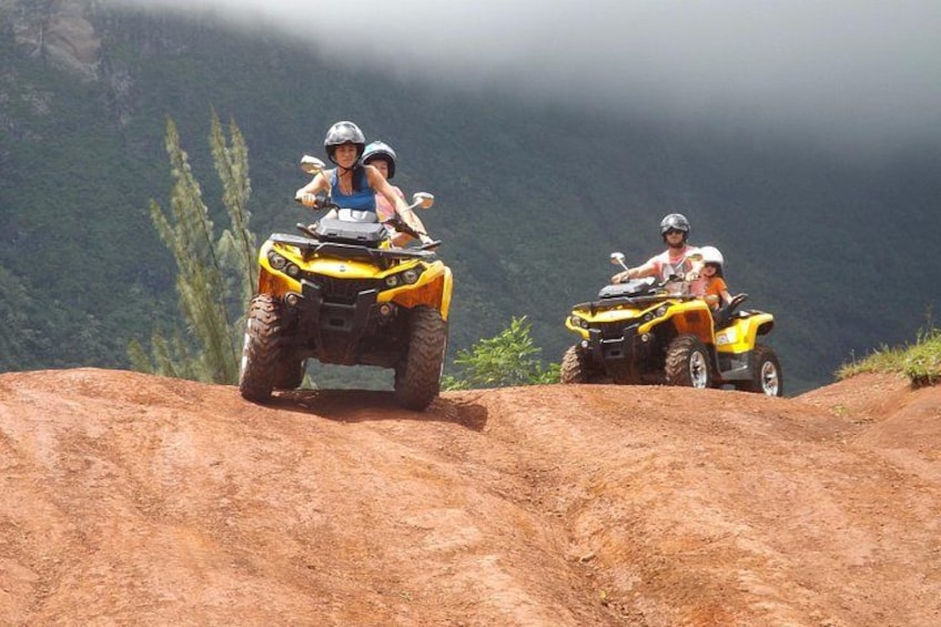 Dos personas en vehículos todoterreno amarillos por un sendero de tierra con montañas al fondo. 1