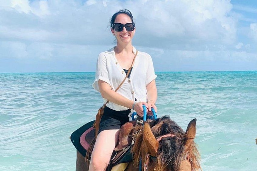A person riding a horse on a boat in turquoise waters. 4