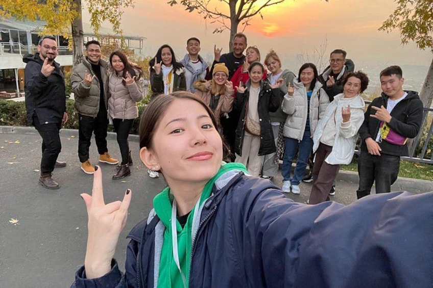 A group of people taking a selfie with a sunset in the background. 5