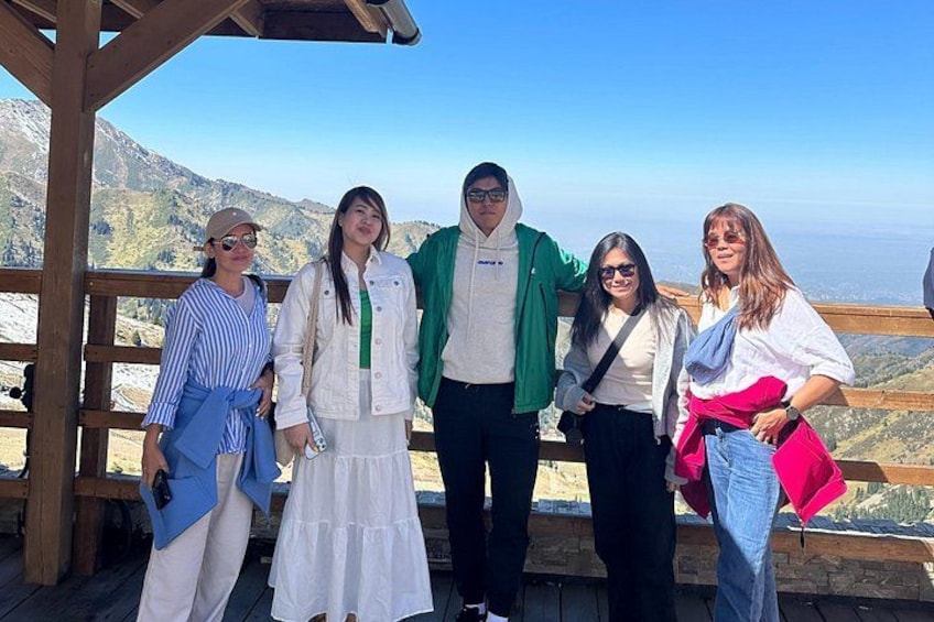 A group of people standing on a wooden platform with a mountainous landscape in the background. 2