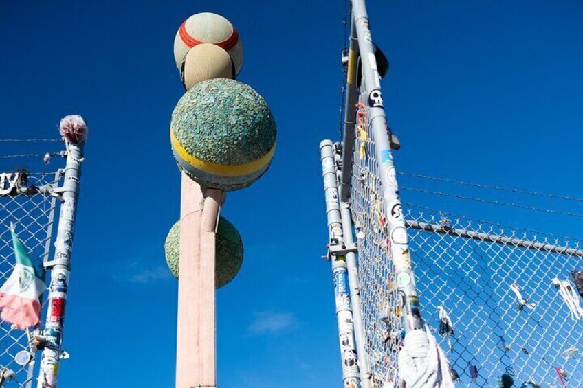 A tall structure with multiple spherical decorations and a chain-link fence. 4