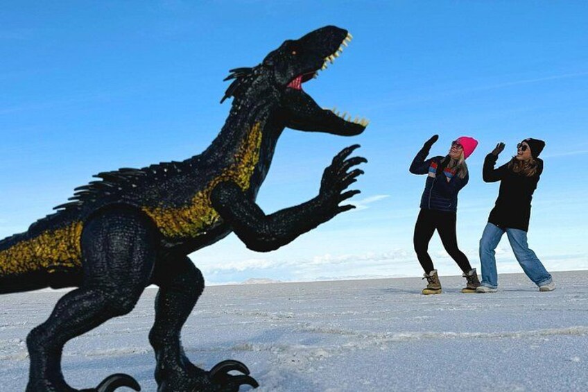 Un modelo de dinosaurio y dos personas en un paisaje nevado. 3