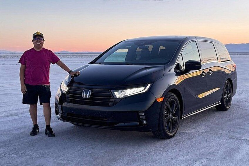 Una minivan Honda negra estacionada sobre una superficie plana cubierta de nieve, con un cielo despejado al fondo. 5
