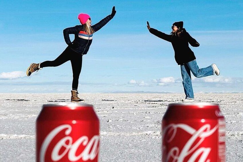 Dos personas bailando en un campo nevado con latas de Coca-Cola al frente. 2