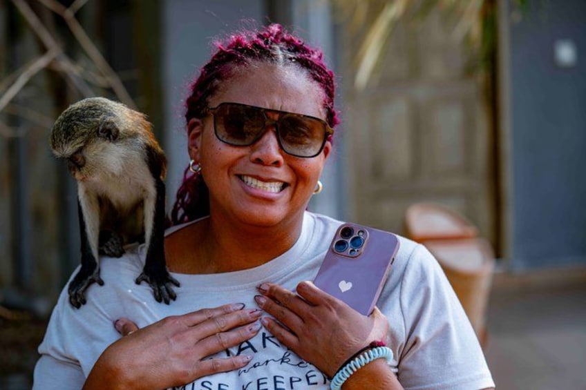 A person holding a smartphone with a monkey perched on their shoulder. 4