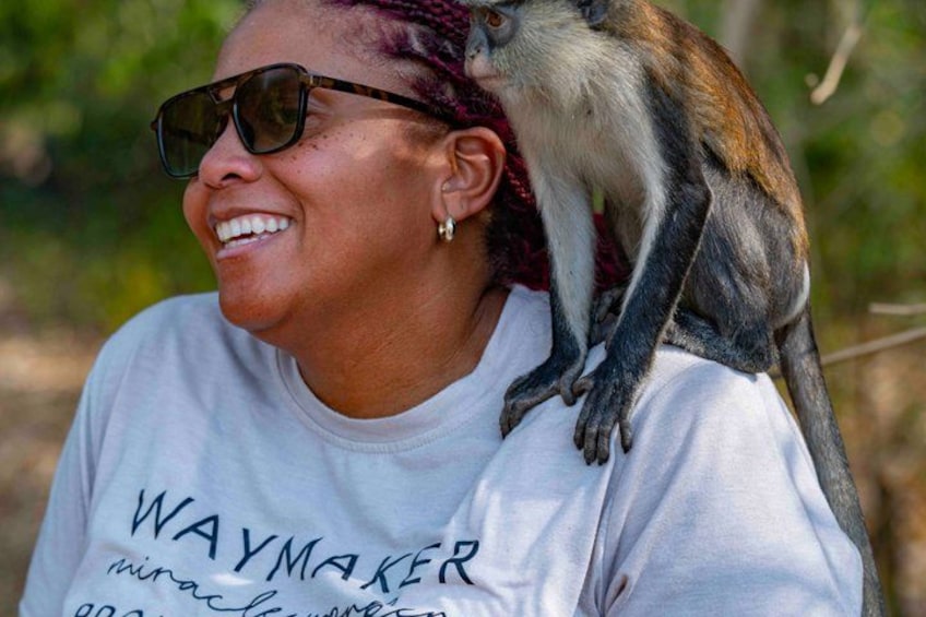 A person wearing a white t-shirt with the text 'WAYMAKER' and a monkey perched on their shoulder. 5