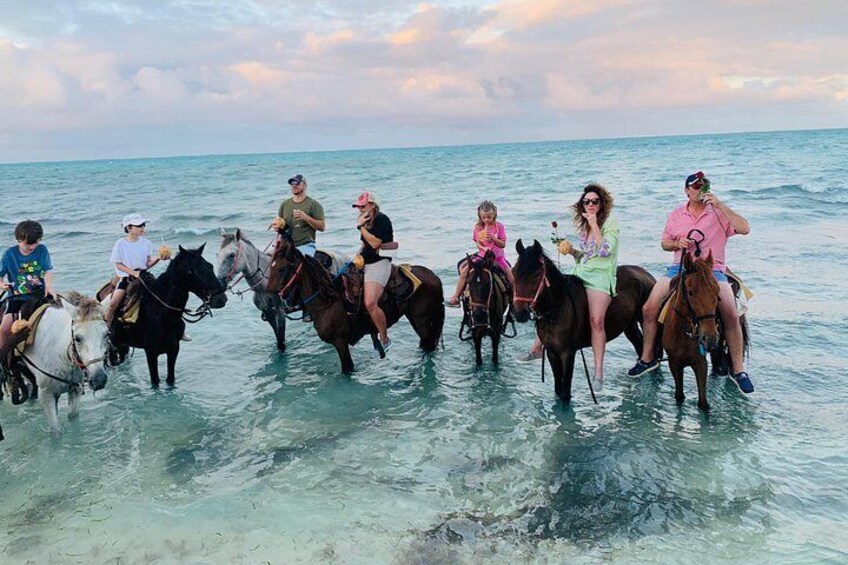 People riding horses in shallow water near the shore. 4