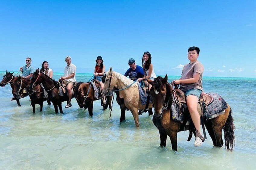 A group of people riding horses on a beach. 3