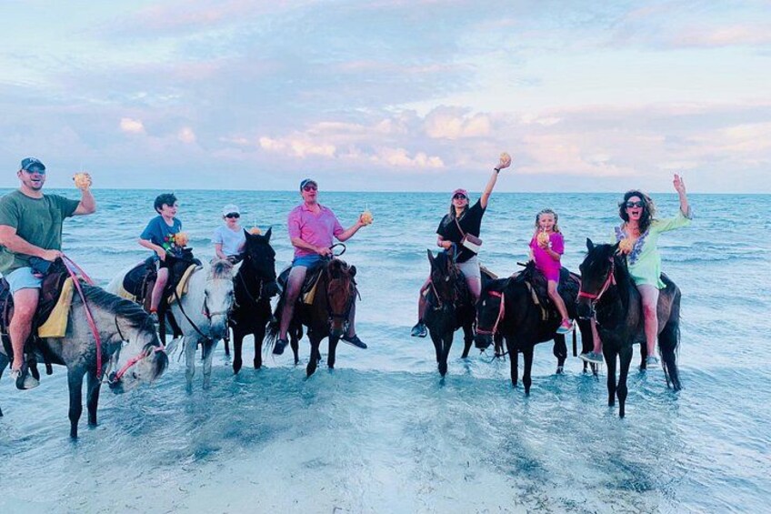 People riding horses on a beach with the ocean in the background. 1
