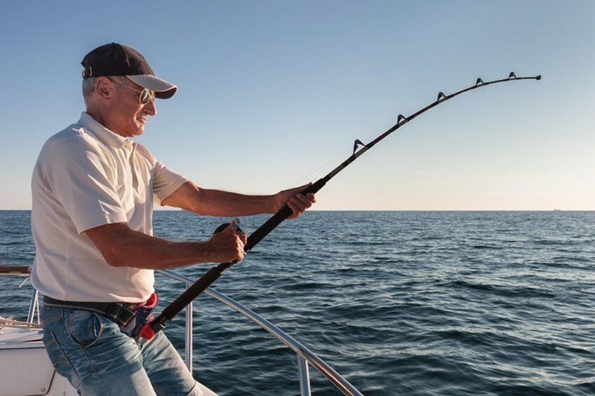 A person fishing on a boat with calm sea and clear sky. 1