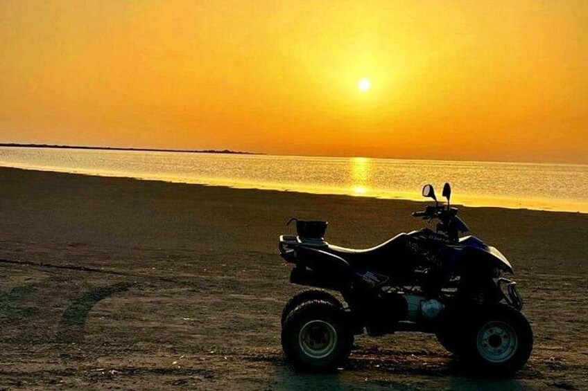 Un quadriciclo parcheggiato su una spiaggia al tramonto. 2