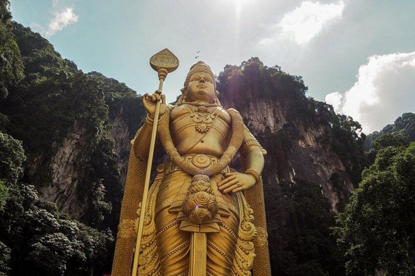 Eine große goldene Statue einer Gottheit mit Dreizack vor einer Berglandschaft. 5