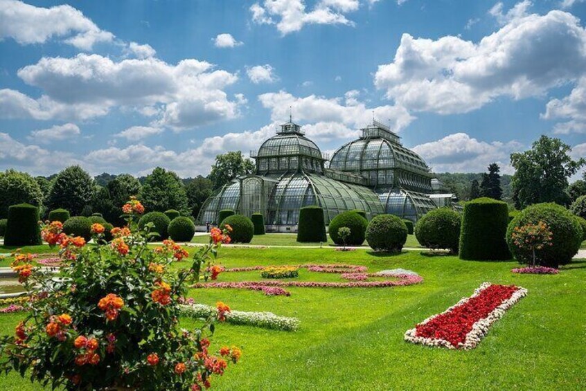 A greenhouse with glass domes, surrounded by manicured gardens and hedges. 4