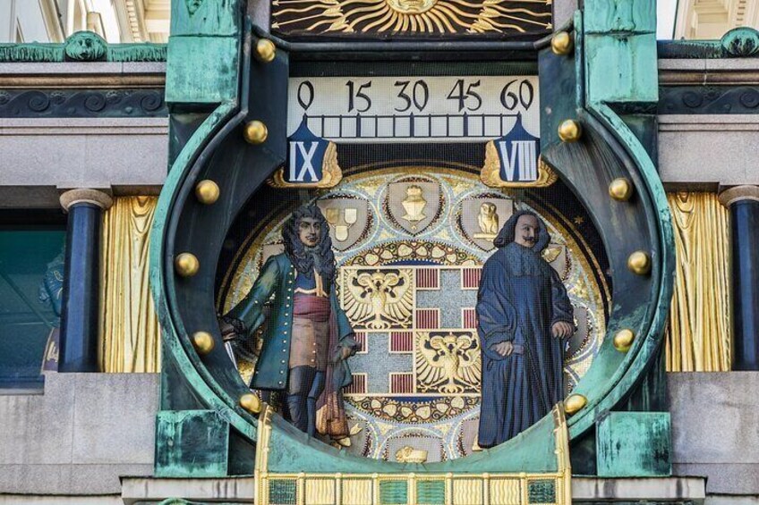 A clock with Roman numerals and two statues. 2