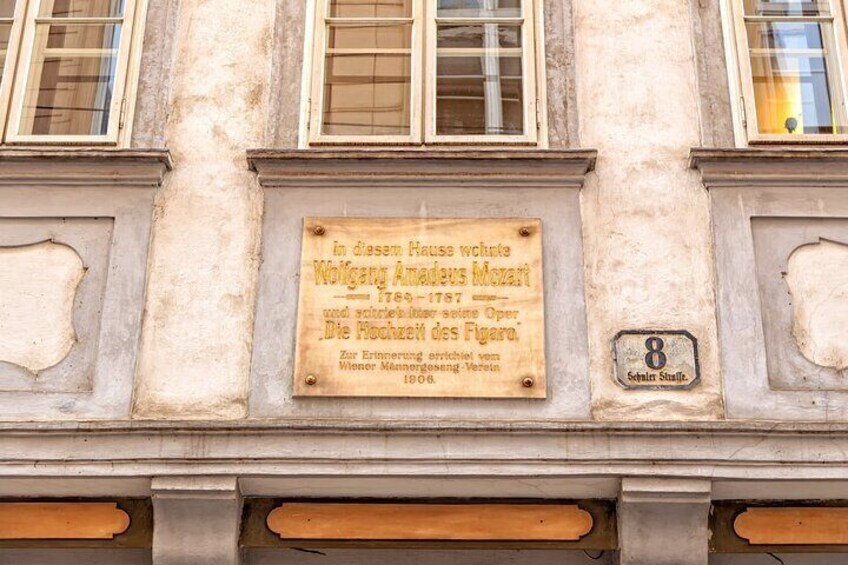 A building facade with a plaque commemorating Wolfgang Amadeus Mozart and a plaque for the 8th Schillerstrasse. 3
