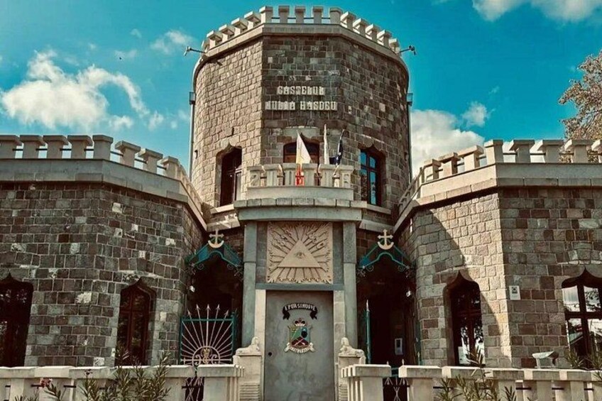 Eine schlossähnliche Struktur mit einem Uhrturm, Bogenfenstern und Steinmauern. 3