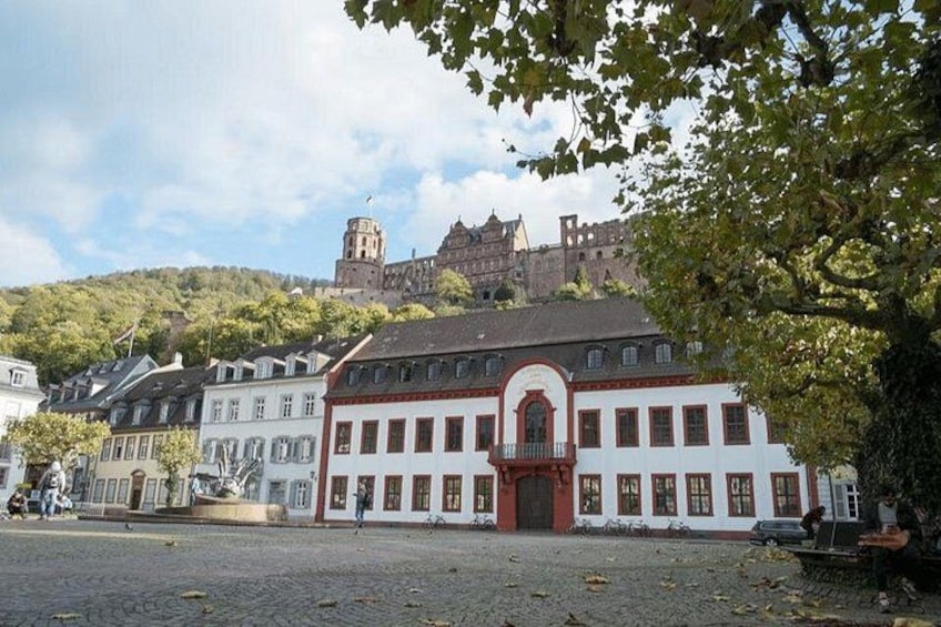 A historic building with a red door, a cobblestone street, and a hill with a castle in the background. 3