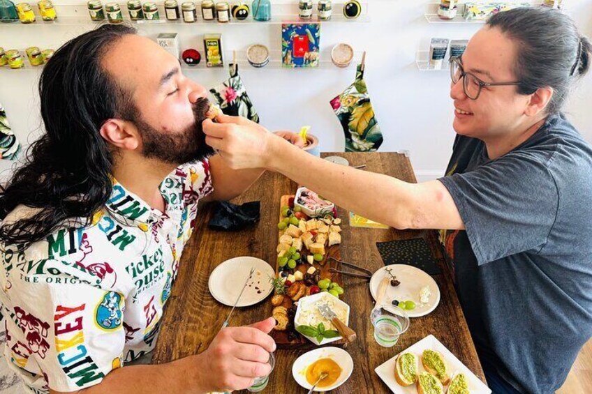Two people eating at a wooden table with various dishes and condiments. 3