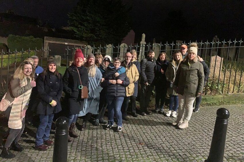 A group of people standing on a cobblestone path at night. 4