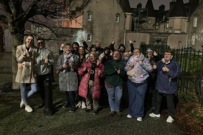 A group of people posing for a photo in an outdoor setting with a building in the background. 5