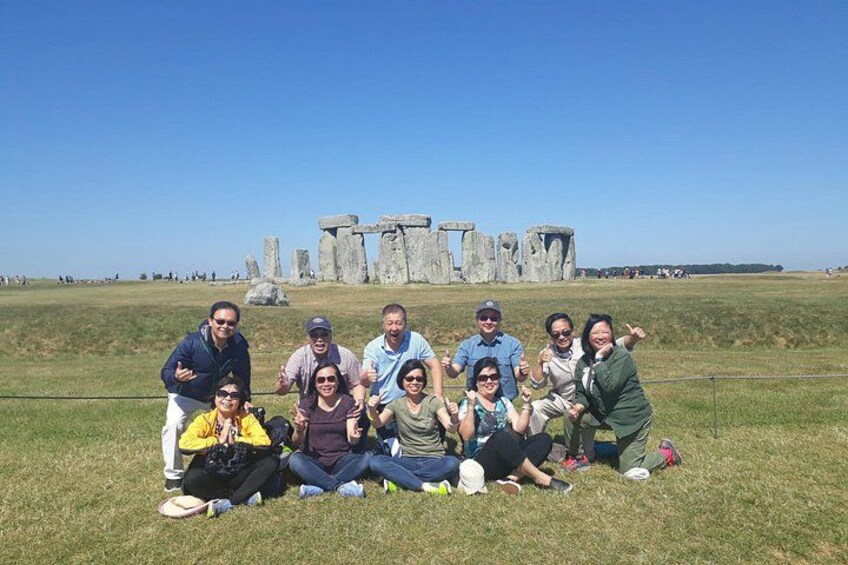 A group of people posing in front of Stonehenge. 3