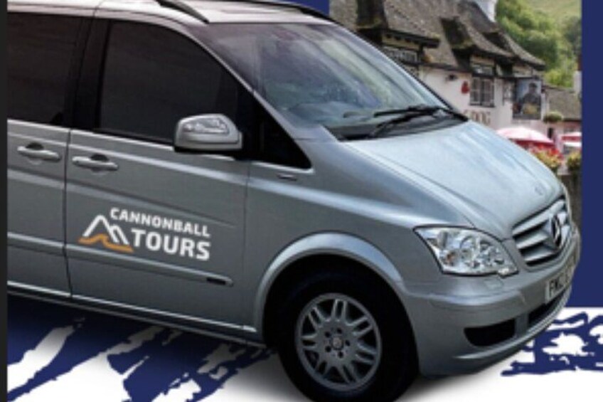 A silver van with 'Cannonball Tours' branding parked in a town. 2