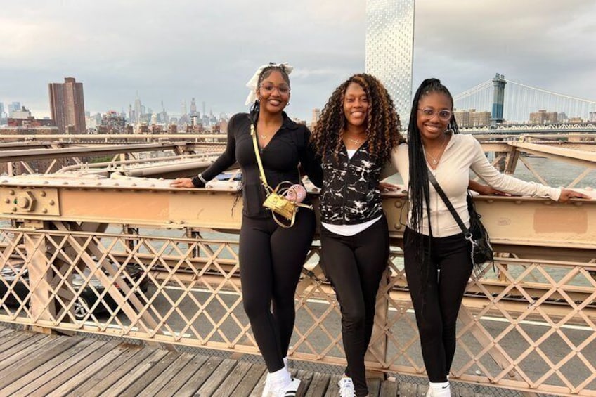 Three people standing on a bridge with a city skyline in the background. 2