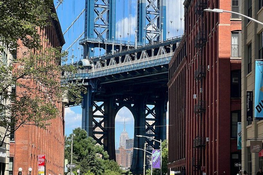 A bridge with a blue metal structure, a red brick building, and a street with a traffic light. 5