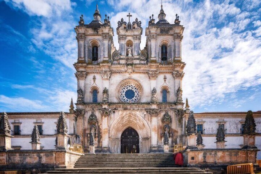 A historic church with a large circular window, a bell tower, and a staircase leading to the entrance. 1