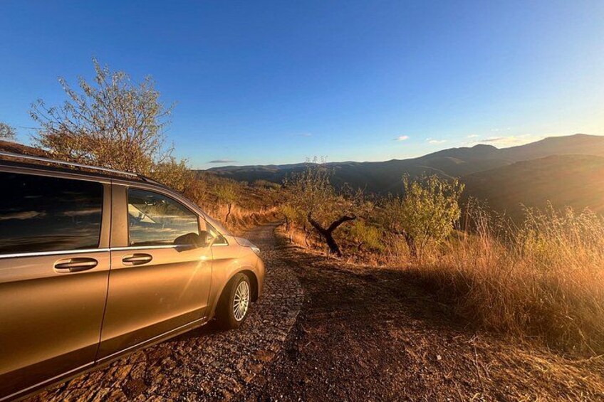 A gold SUV parked on a dirt path with a mountainous landscape in the background. 4