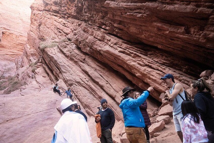 Eine Gruppe von Wanderern durchquert einen Canyon mit roten Felsformationen. 2