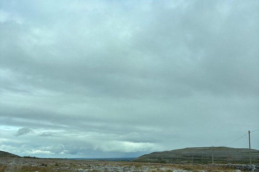 Cielo nublado sobre un paisaje cubierto de hierba con colinas onduladas y una línea de alta tensión. 1