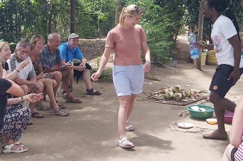 A person walking on a dirt path, surrounded by a group of seated individuals. 2