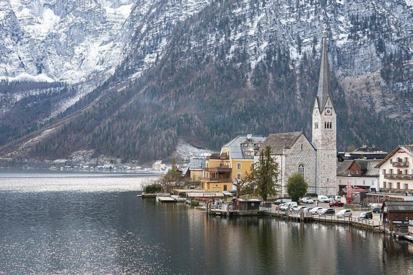 Un paese sul lago con una chiesa, edifici e montagne innevate sullo sfondo. 2
